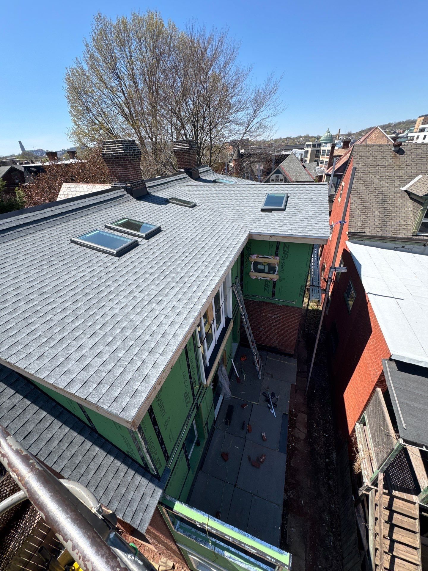 New light grey shingle roof with three skylights on a city home addition