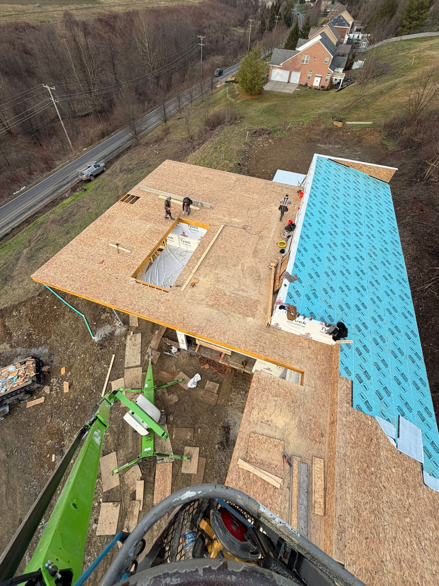 Aerial view of crew sheathing a new roof deck with underlayment being rolled out