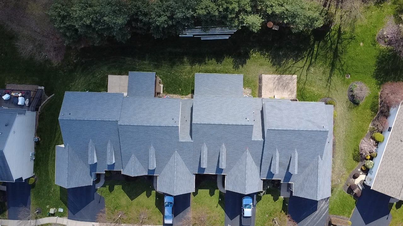 Overhead drone view of finished shingle roofs on a row of townhomes
