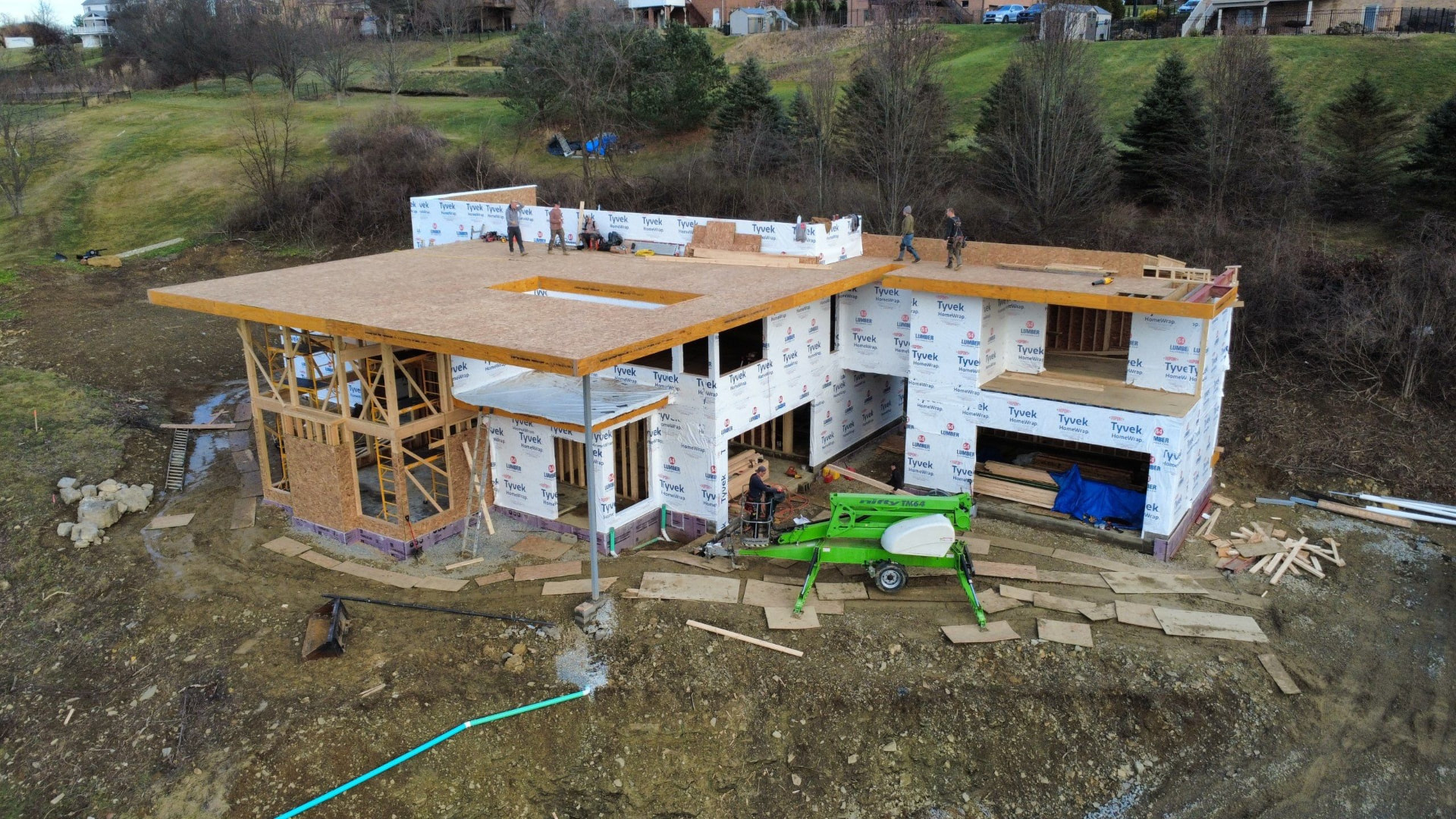 Aerial view of a custom home under construction with Tyvek wrap and new roof decking