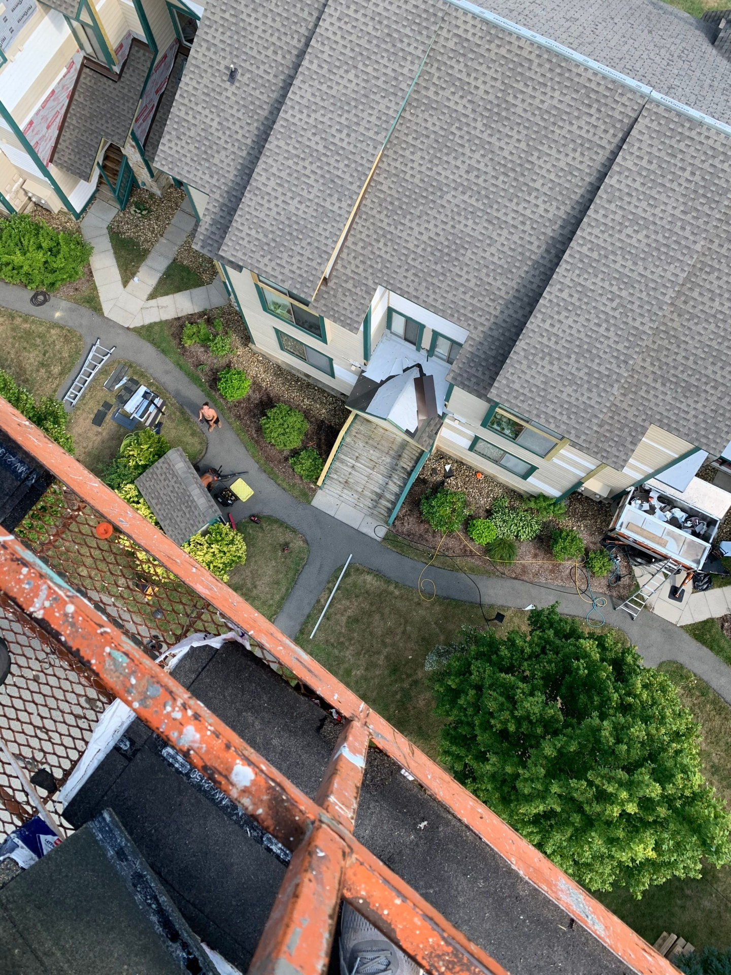 View from the top of a condo building mid re-roof with new shingles and staged materials below