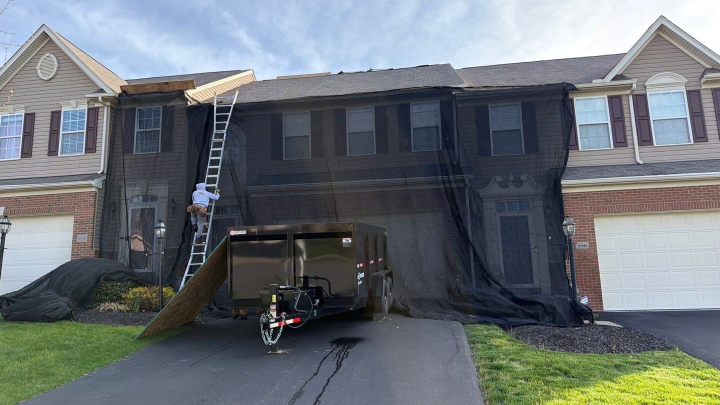 Townhome front elevation fully draped in protective netting during a roof tear-off