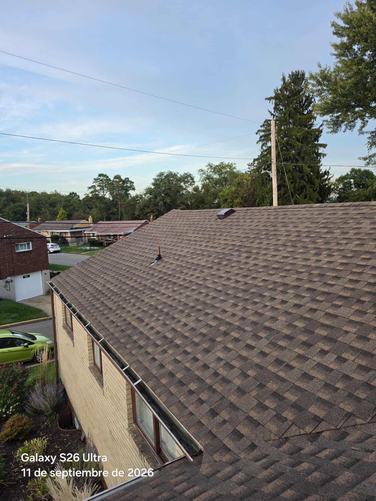 Sloped roof with brown architectural shingles on a brick home with a new plumbing vent pipe