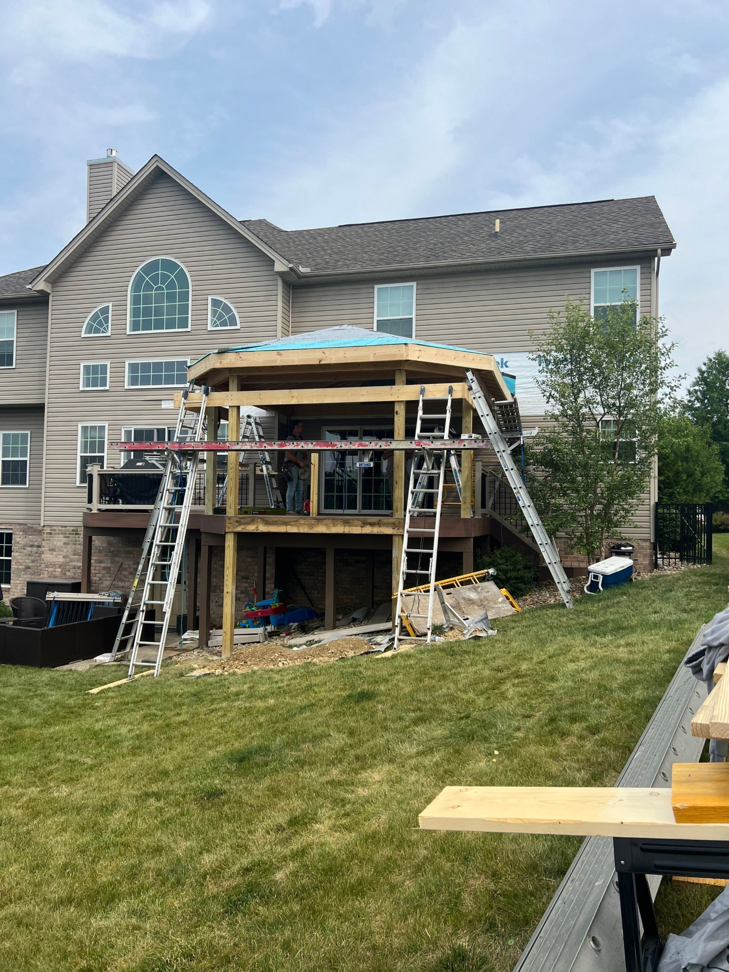 Covered deck gazebo framing with hip roof sheathing on a two-story home
