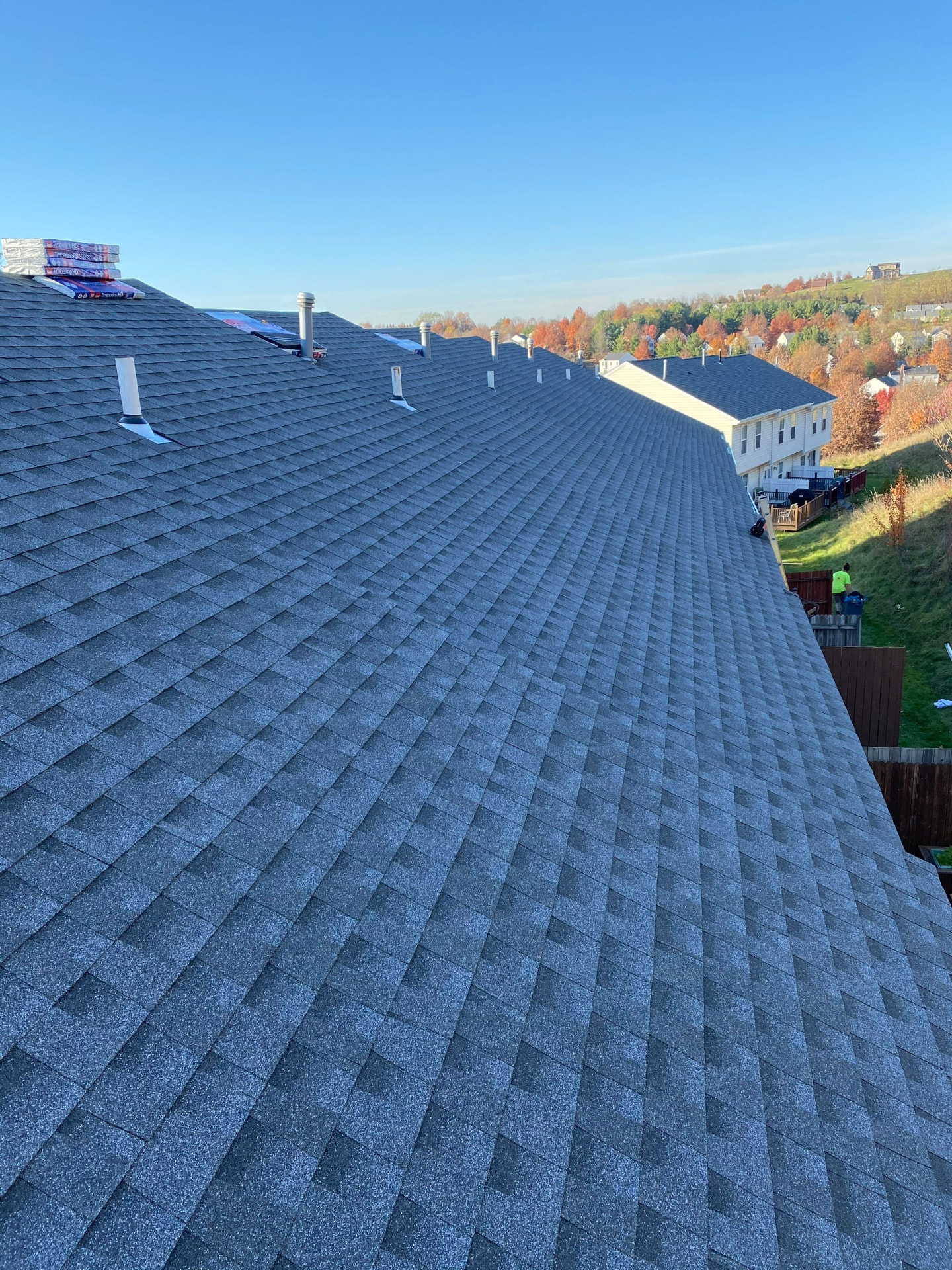 Newly installed grey architectural shingles running along a long townhome ridge line