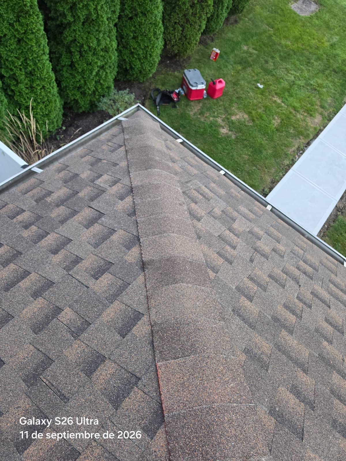 Hip roof corner with brown architectural shingles, new ridge cap and aluminum gutters with clips