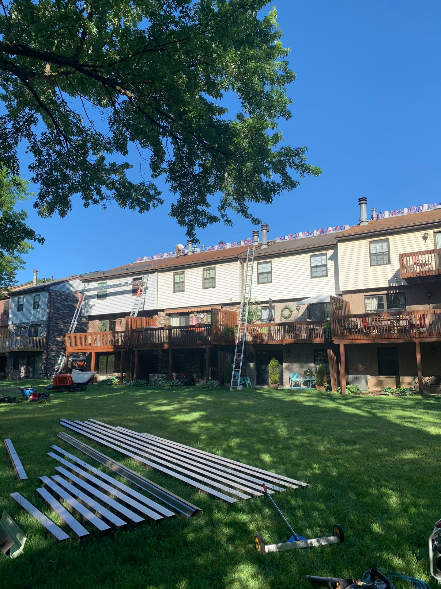 Townhome complex with ladders set and new metal trim stock staged on the lawn