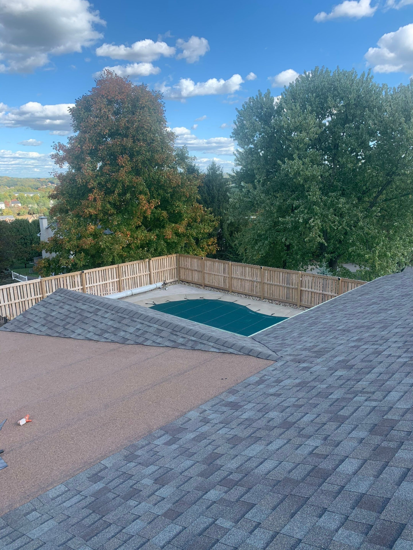Freshly shingled roof overlooking a fenced backyard pool on an autumn day