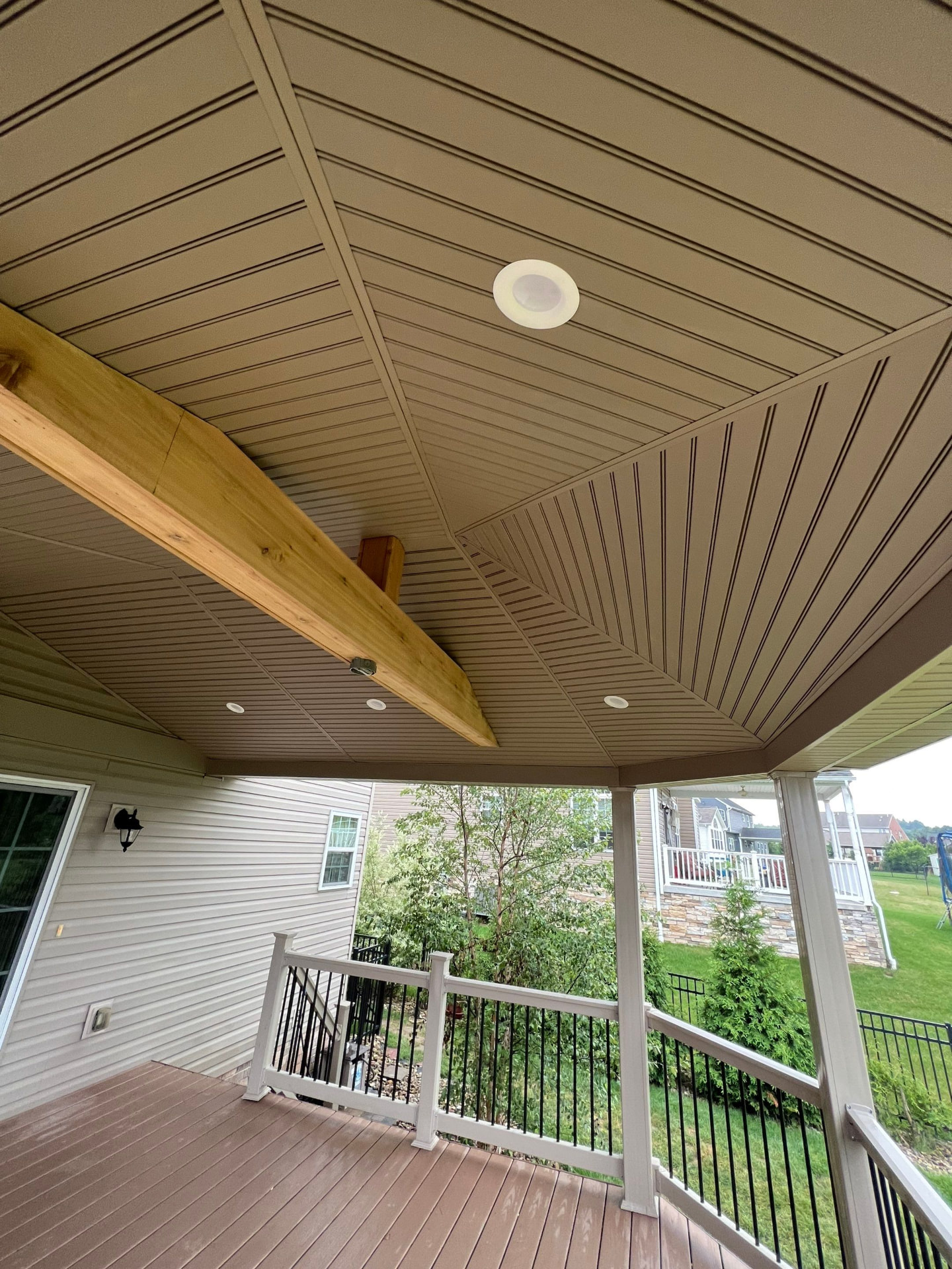 Finished covered porch with beadboard ceiling, cedar beam and recessed lights over composite decking