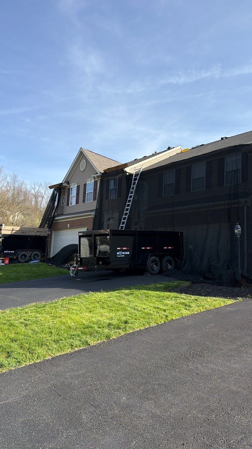 Dump trailers staged in a driveway during a townhome roof tear-off