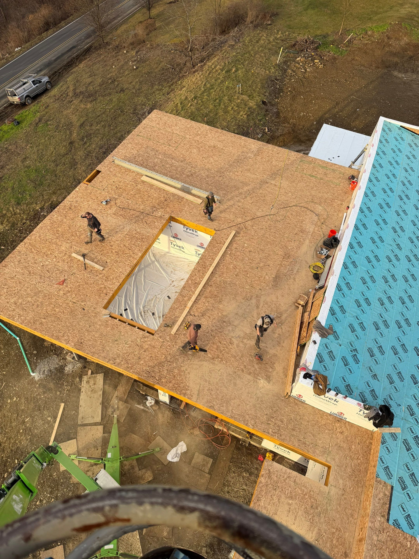 Overhead view of crew installing roof decking on a large new build with StormGuard on the gable