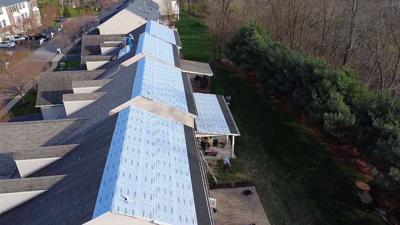 Drone view of a townhome row with blue synthetic underlayment installed across the main slope