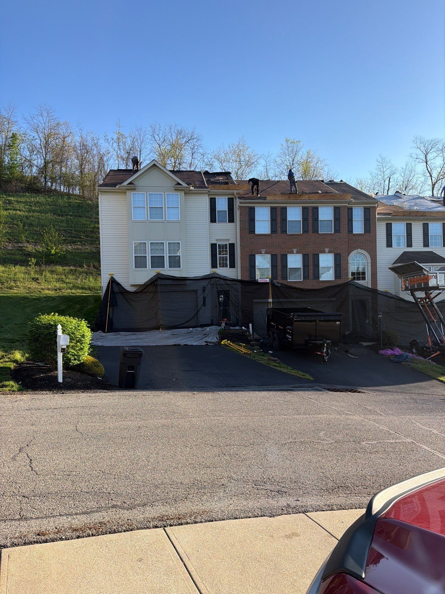 Crew working across townhome roofs with exposed decking and full property tarping