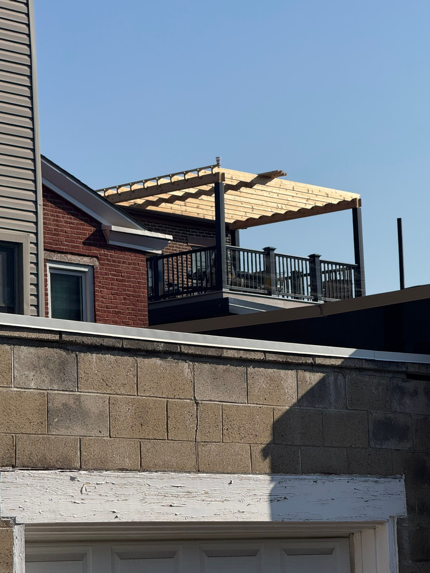 Rooftop deck with black aluminum railing and a new cedar pergola over a city garage