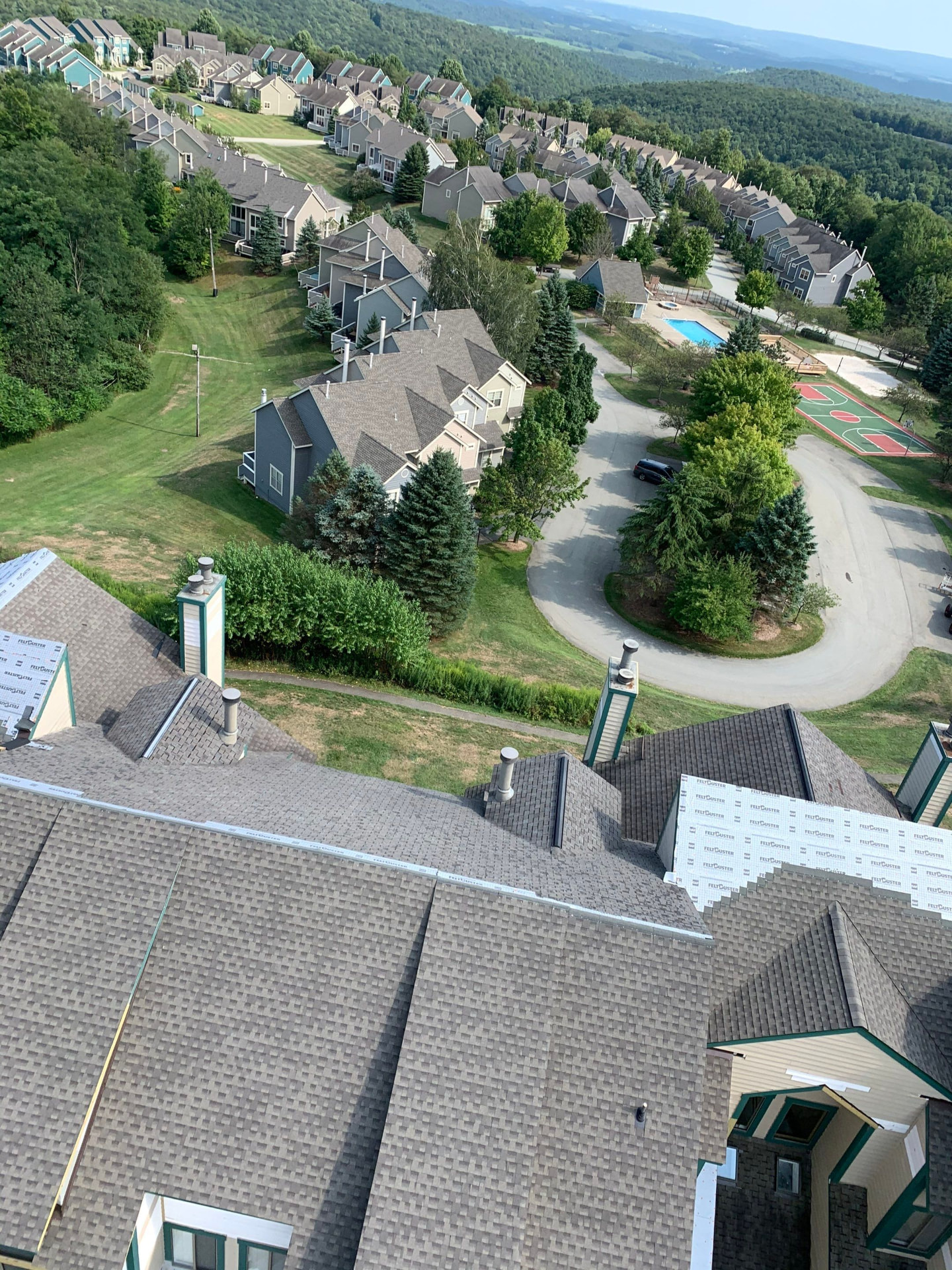 Aerial view of a townhome roof with GAF FeltBuster underlayment and finished shingle sections