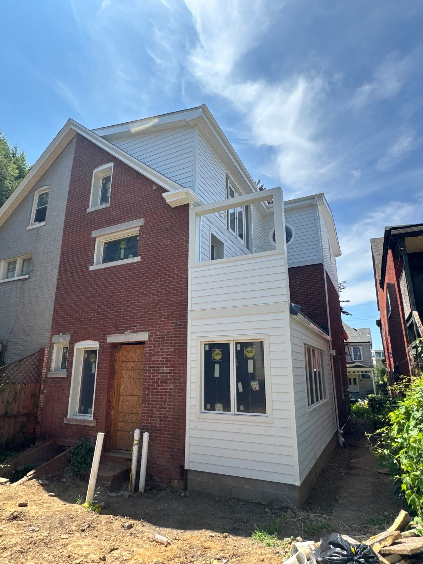 Brick city home with a new white siding addition, trim and Pella windows installed