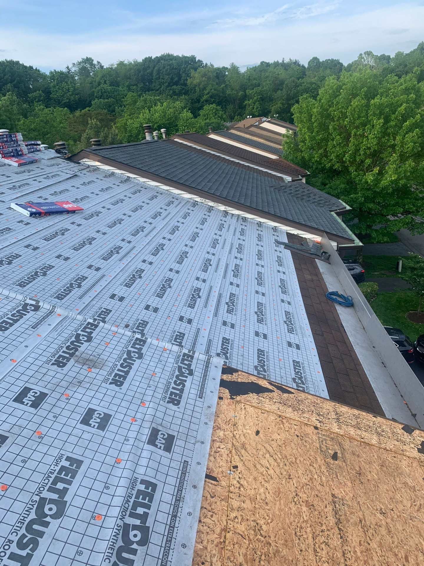 Large townhome roof slope covered in GAF FeltBuster underlayment with Timberline bundles staged
