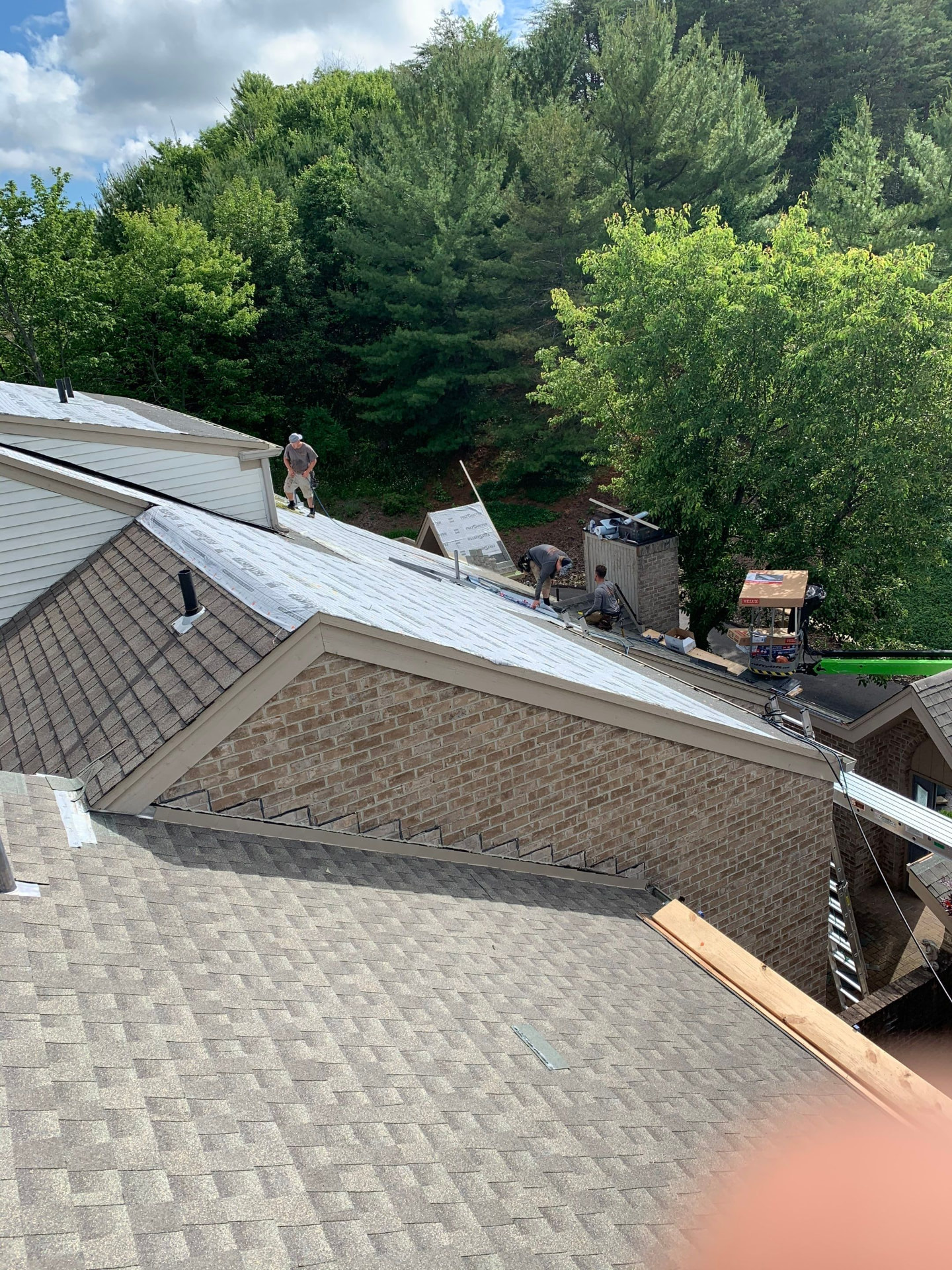 Roofing crew installing Velux skylights and underlayment on a large residential roof