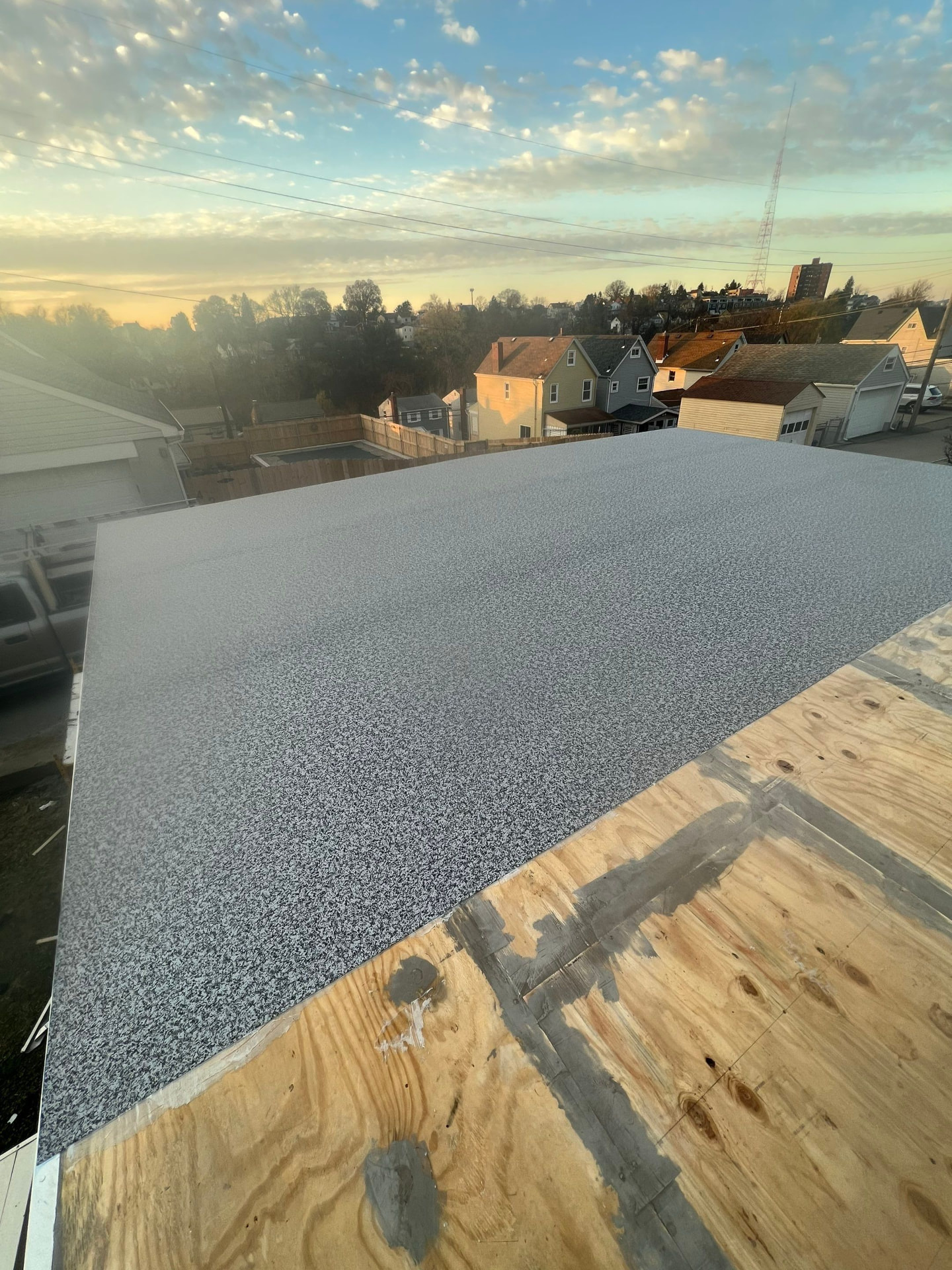 Granulated modified bitumen flat roof membrane installed at sunrise over new plywood decking