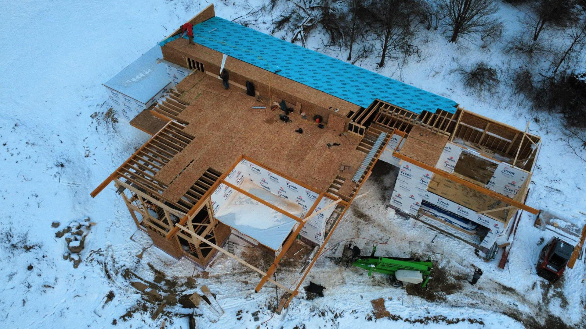 Winter drone view of a new build with framed floor deck and blue roof underlayment
