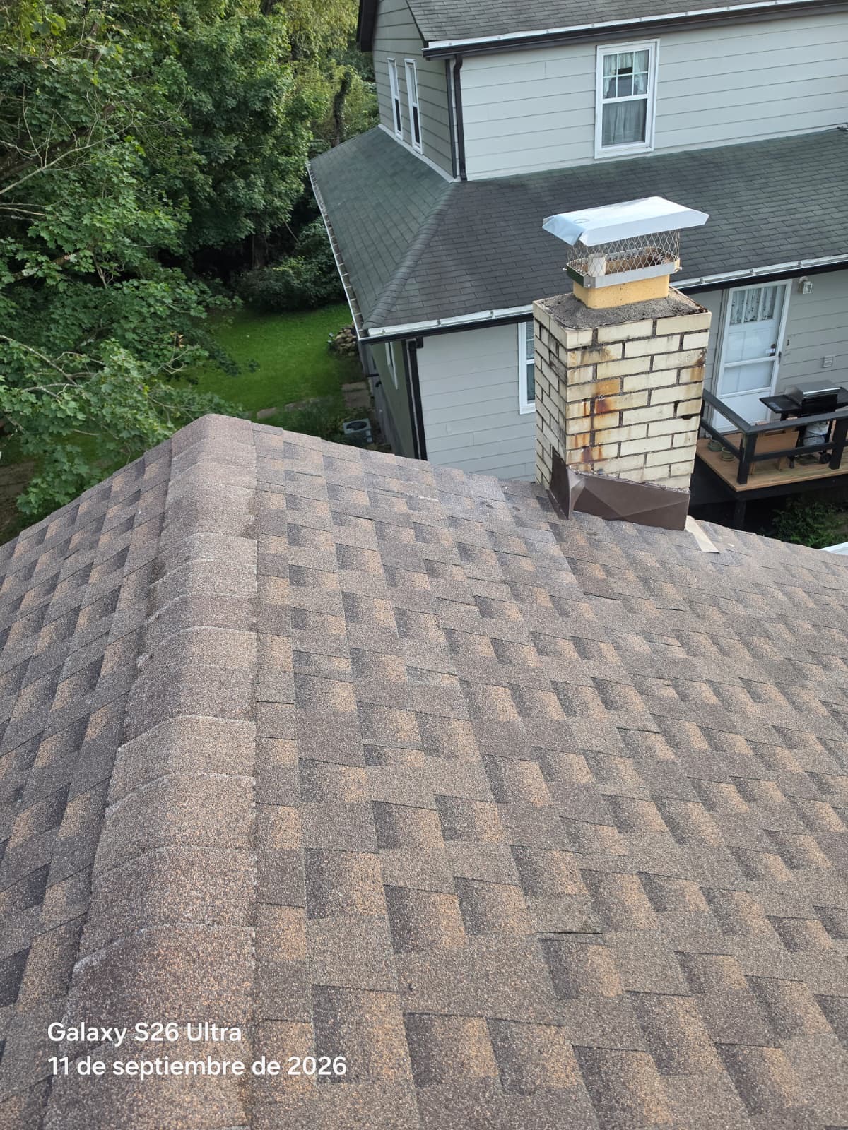 Gable roof with brown architectural shingles and a brick chimney with new metal cap and flashing