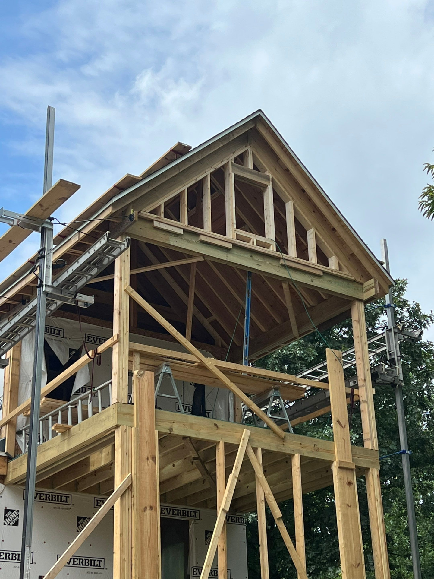 Two-story covered porch framing with gable roof structure and scaffolding in place
