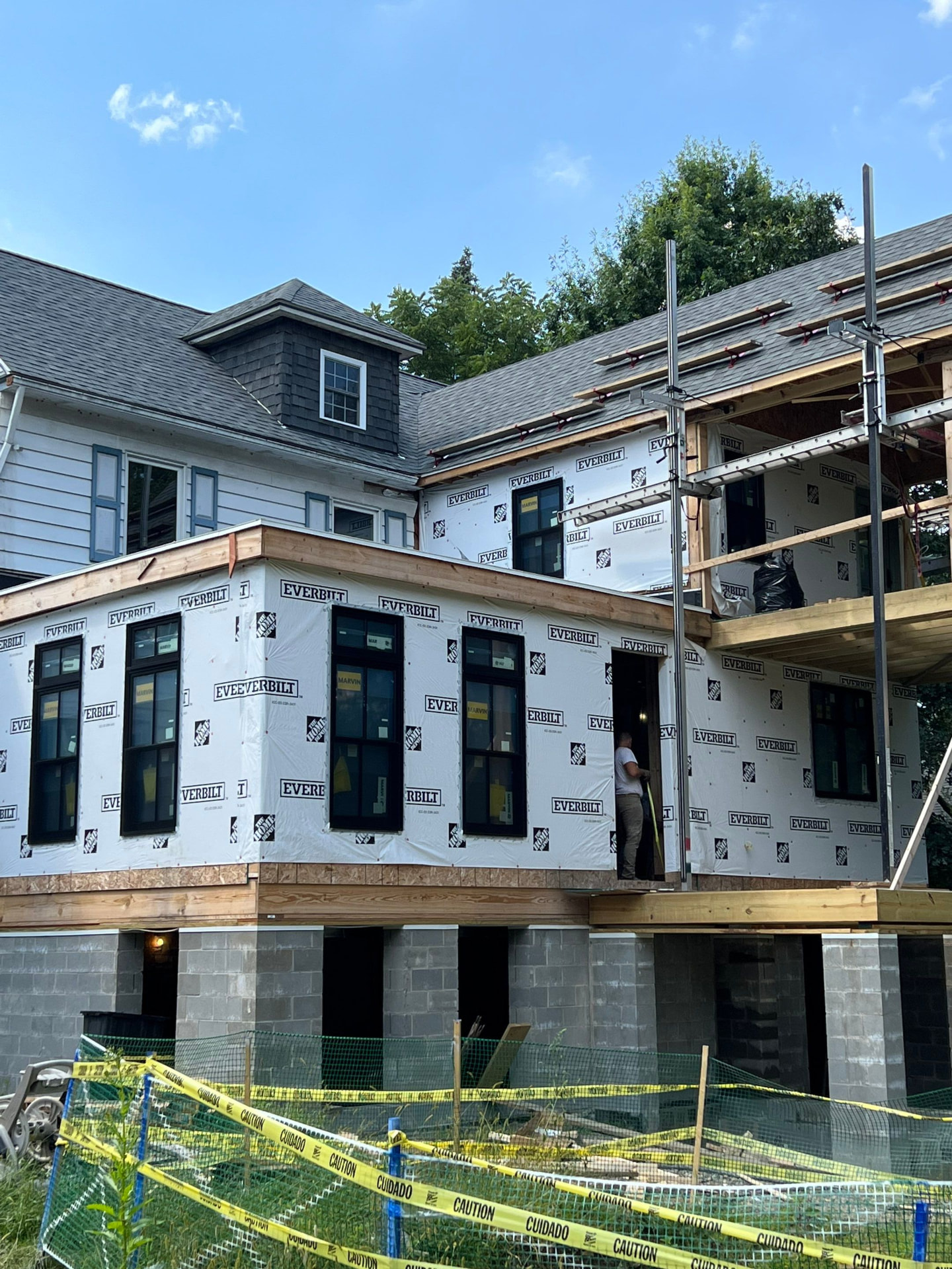 Large two-story addition wrapped and windowed with new shingle roof and scaffolding