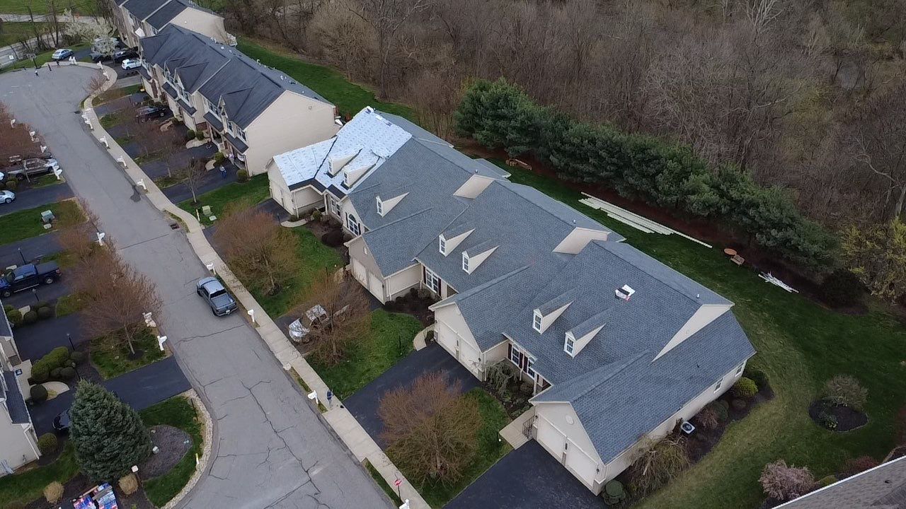 Aerial view of a finished condo building with new grey architectural shingles and dormers