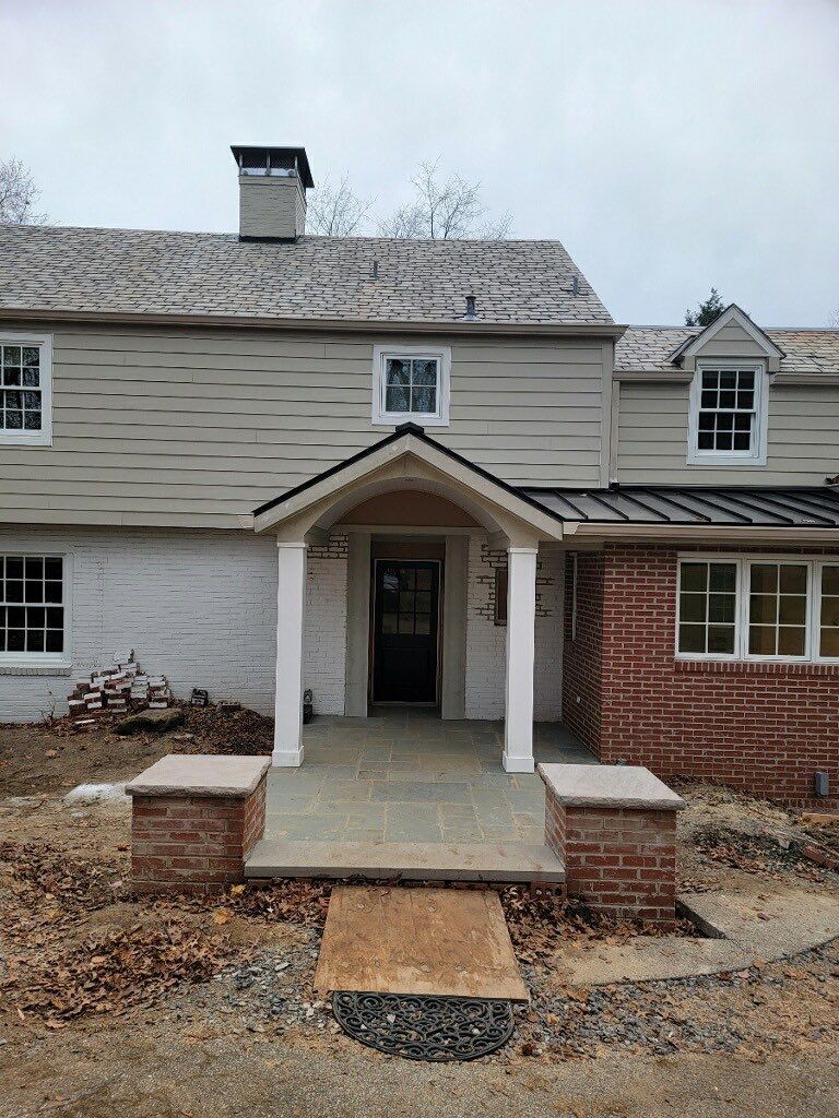 Finished home entry with new portico, standing seam metal roof accent and bluestone patio