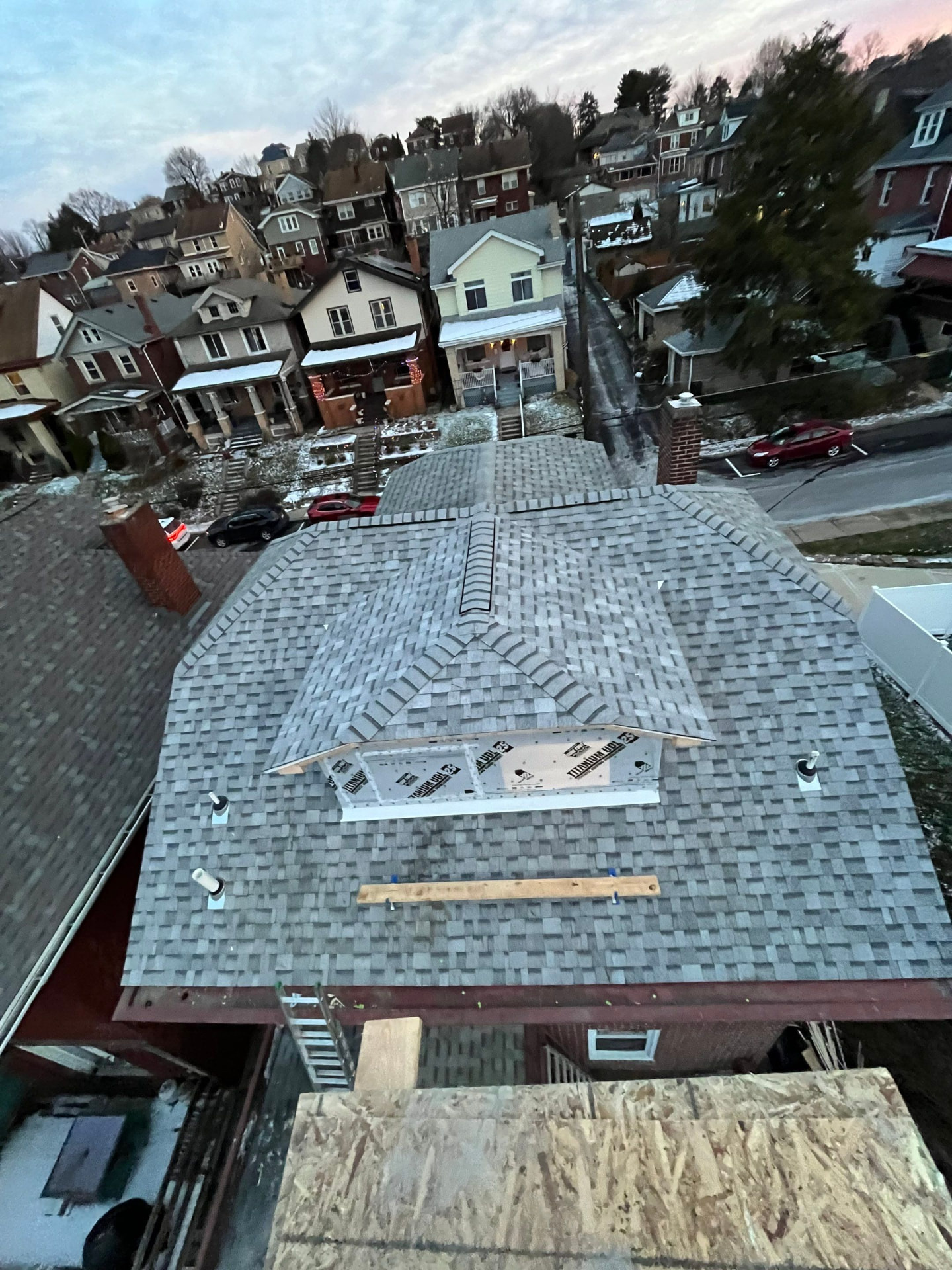 Aerial view of a freshly shingled Pittsburgh hillside home with ridge vent and new dormer underlayment
